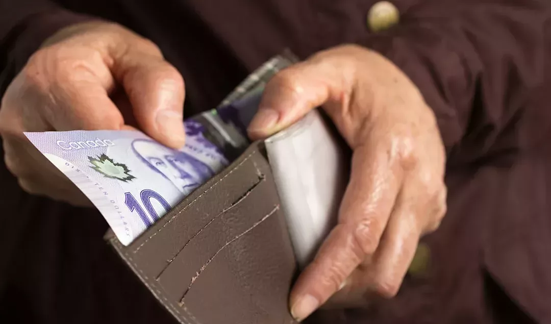 A man holding a wallet with money inside.