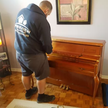 A mover is packing and moving a piano.