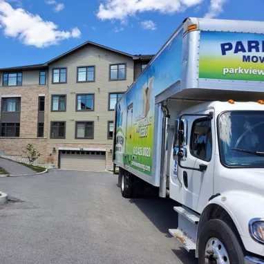 A moving truck parked in front of an apartment building by Barrhaven Movers.