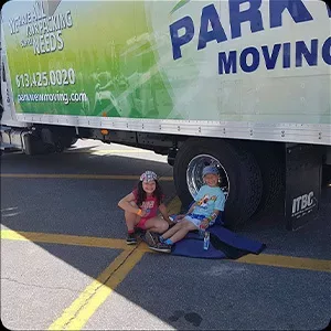 Two children sitting on a skateboard in the shade of a parked moving truck, captured in photos.