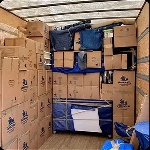 A neatly organized moving truck packed with labeled boxes, photos, and furniture wrapped in protective blankets.