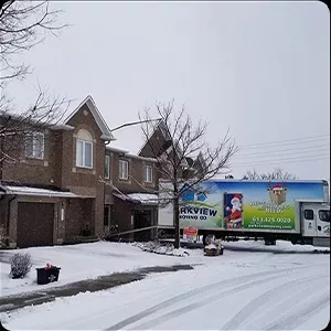 A moving truck parked on a snowy residential street, captured in photos.