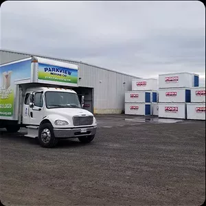A moving company truck parked in a lot with several portable storage containers, captured for a photo gallery.
