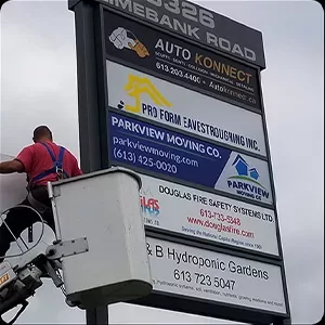 A person on a cherry picker servicing a roadside advertisement billboard, capturing images for documentation.