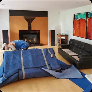 A person relaxing on a couch under a blue blanket in a modern living room with a fireplace, captured in beautiful photography.
