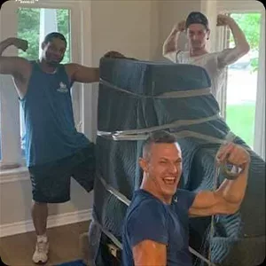 Three happy movers flexing their muscles next to a stack of wrapped chairs in a photography session.