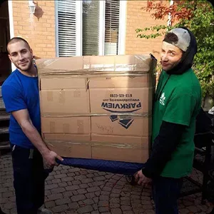 Two men transporting a large cardboard box using a hand truck, captured in images.