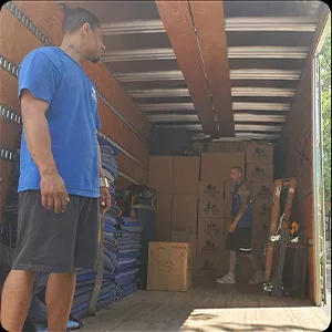 Two people standing inside a partially loaded moving truck, taking photos.