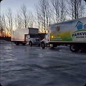 Two moving trucks parked on an icy lot captured in stunning photography during sunrise or sunset.