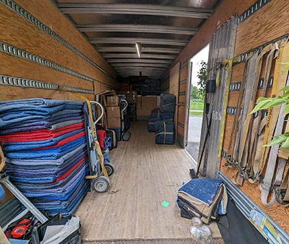 The interior of a long-distance moving truck equipped with straps, moving boxes, protective pads, and tools for safe transport.