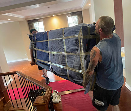 Two Parkview Moving Co. movers preparing to carefully move furniture down a stairway, ensuring safety and protection during the move.