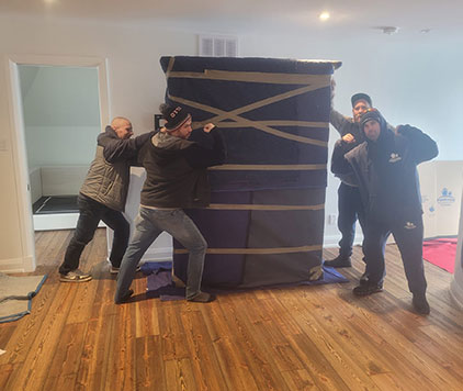 Four Parkview Moving Co. movers wrapping a large piece of furniture for protection, preparing it for a safe move.