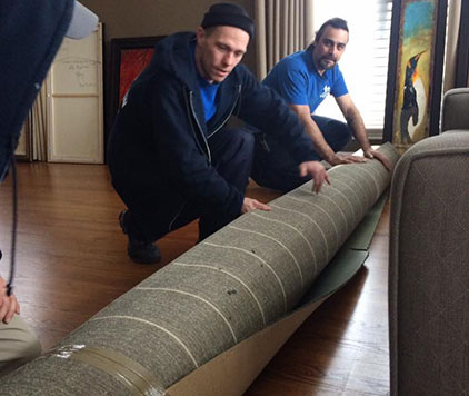 Two professional movers carefully rolling up an area rug for safe transport with Parkview Moving.