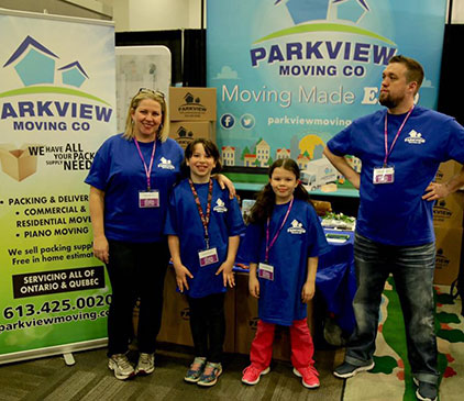 Parkview Moving Co. team proudly standing in front of their local booth, highlighting a variety of professional moving services.