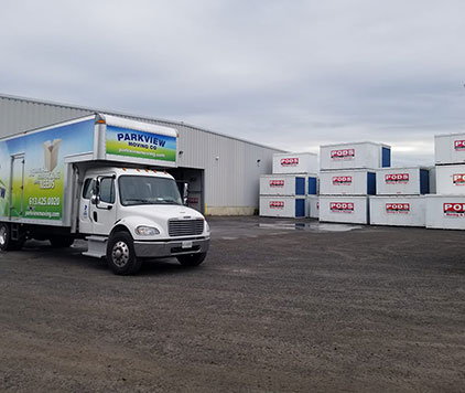 Parkview Moving Co. truck parked outside a storage warehouse with stacked storage containers nearby in Ottawa.