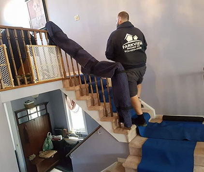 Shaw, a leader at Parkview Moving, installing protective padding on the banister and steps to safeguard the home during a move.