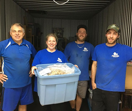 Four smiling employees standing inside a moving truck, showcasing teamwork and professionalism during a move.