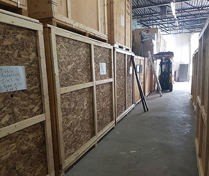 Long-term storage facility with large wooden crates along the walls and a forklift in the background at Parkview Moving in Ottawa.