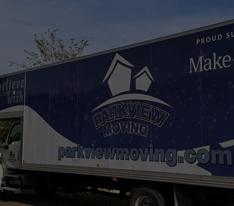 Three Parkview Moving trucks parked in a row, with the largest moving truck proudly supporting the Make-A-Wish Foundation.