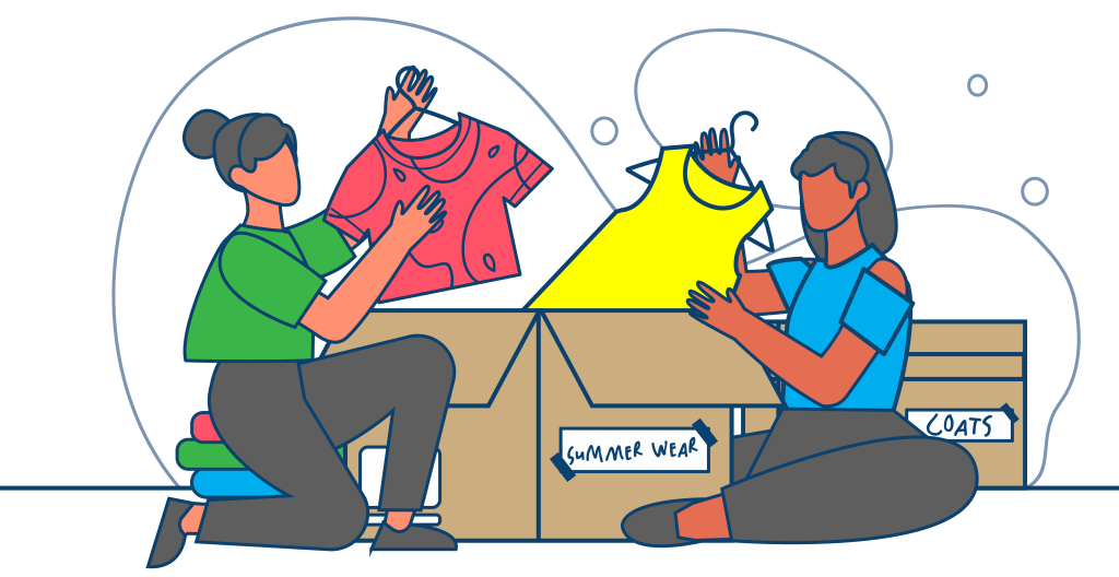 Two women collaborate to sort and pack clothes into labeled boxes, preparing for various seasons during the move.
